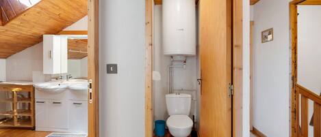 A wooden interior with a white toilet, a sink, and a mirror in a small bathroom.