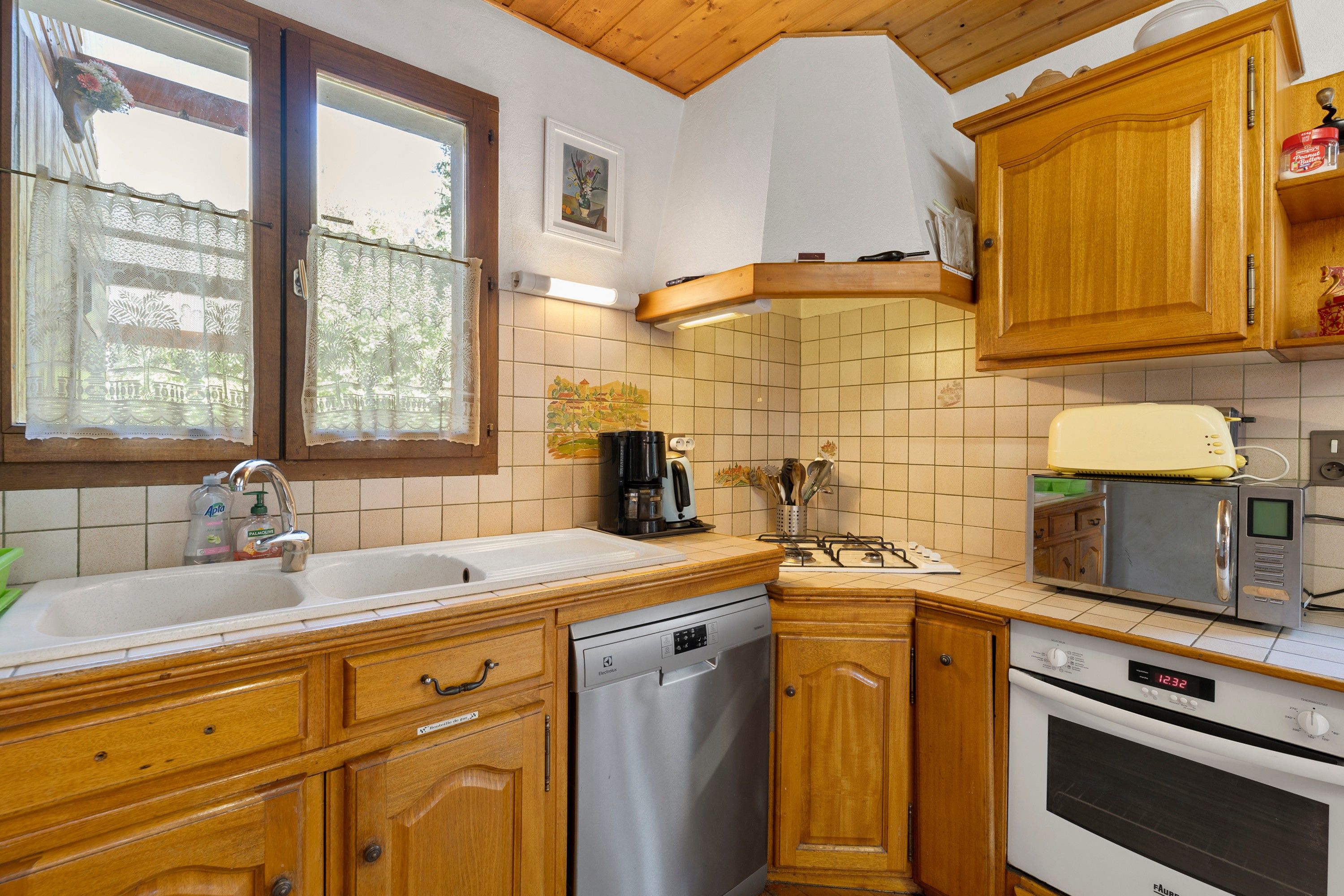 A kitchen with wooden cabinets, a dishwasher, a microwave, and a stove.