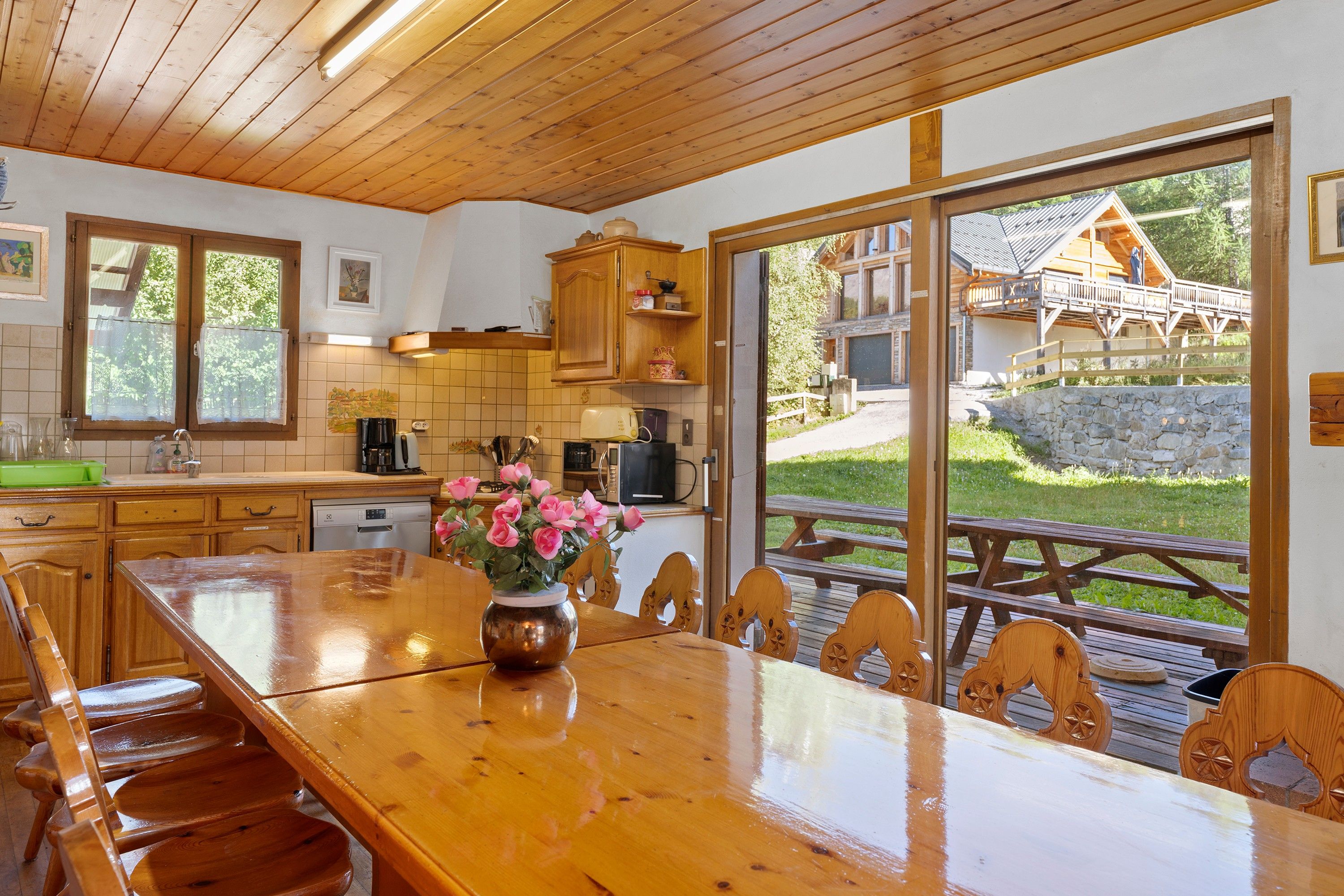 Cozinha espaçosa com armários de madeira, mesa de jantar com cadeiras e vista para o exterior.