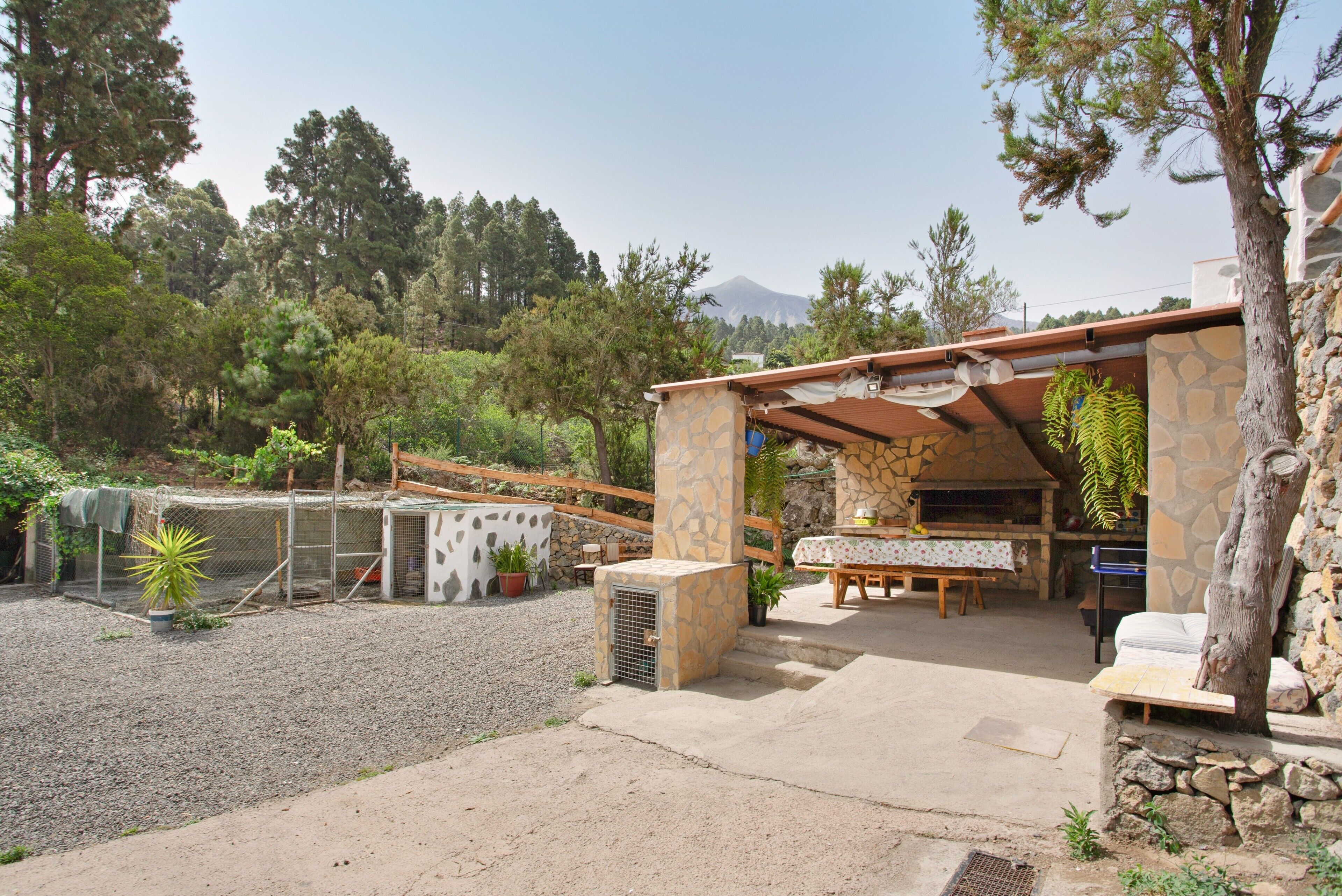 Un patio con una mesa y sillas de piedra, rodeado por un muro de piedra y una valla de madera.