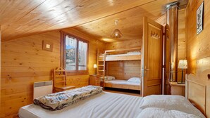 Une chambre dans un chalet en bois, avec un lit superposé, un bureau et une fenêtre donnant sur un paysage agréable.