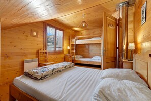 Une chambre dans un chalet en bois, avec un lit superposé, un bureau, une chaise et une fenêtre.