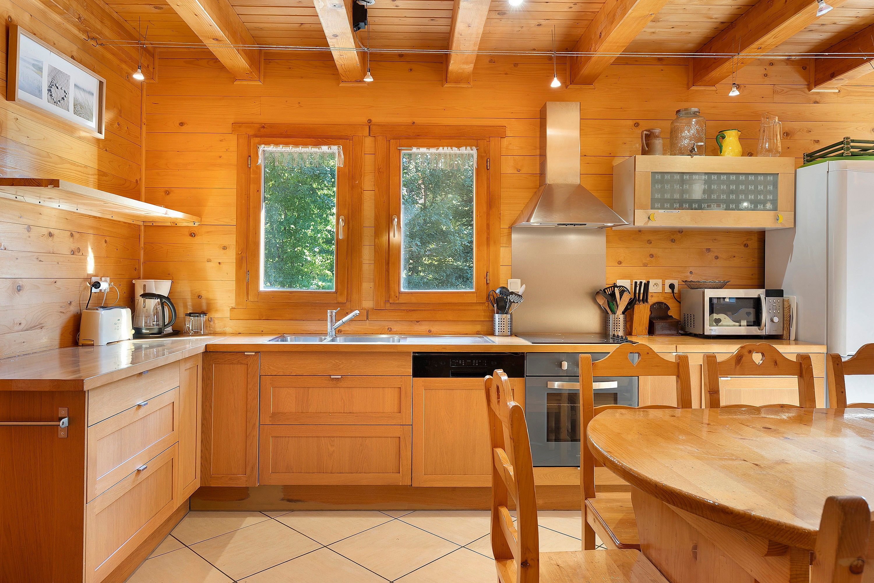 Une cuisine rustique aménagée dans une cabane en bois, avec un évier, une cuisinière, un four à micro-ondes et des placards en bois.