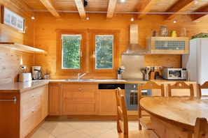 Eine Holzhütte mit einer Küche, inklusive Spüle, Herd, Mikrowelle und Holzschränken.