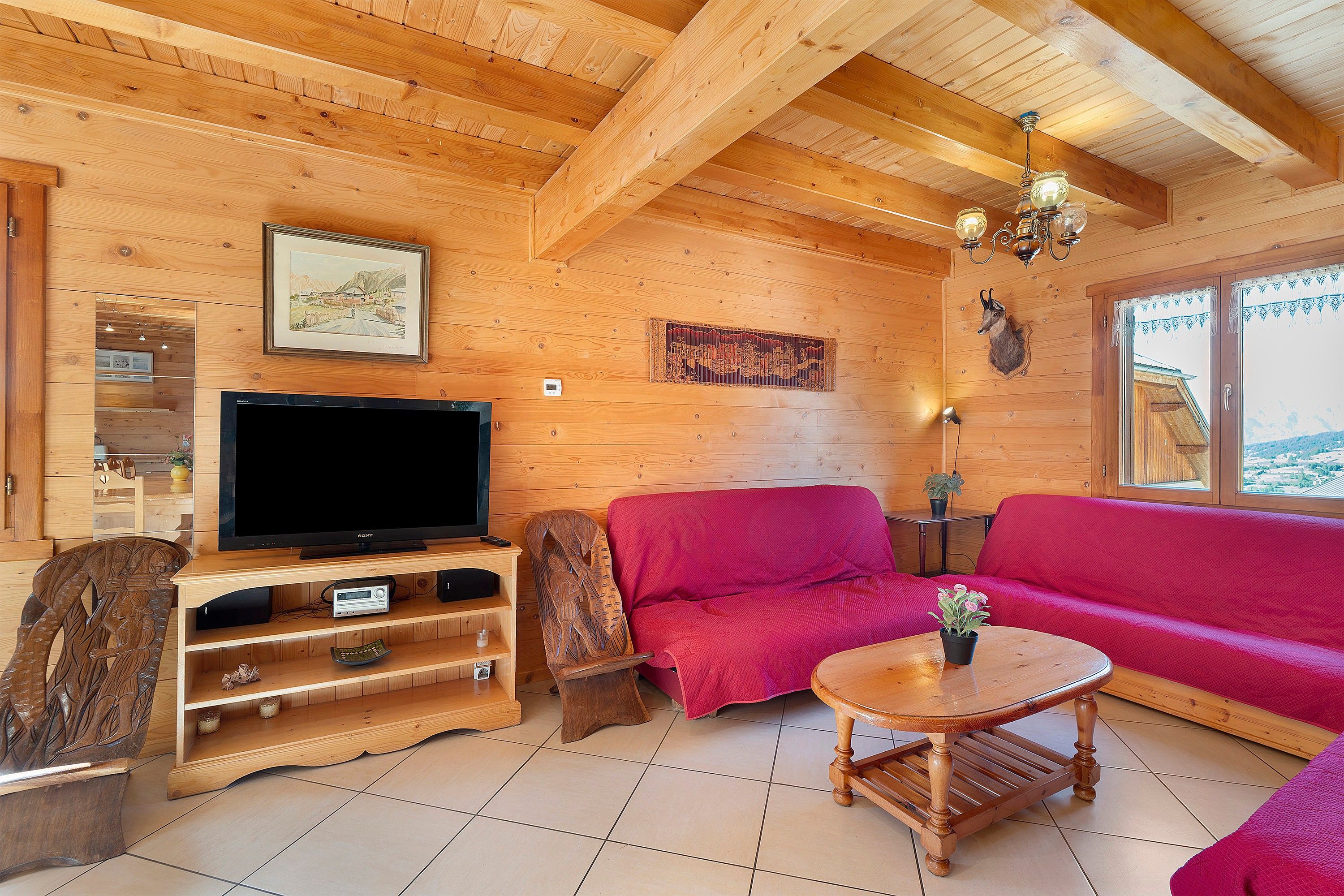 Un interior de madera con una televisión, un sofá rojo y una mesa de centro de madera.