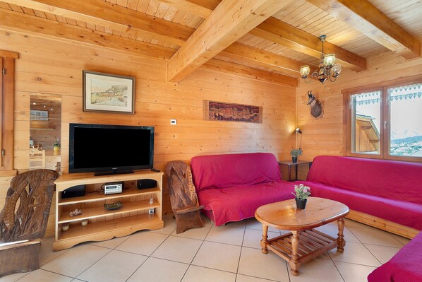 Ein Holzinnenraum mit Fernseher, rotem Sofa und Couchtisch aus Holz.