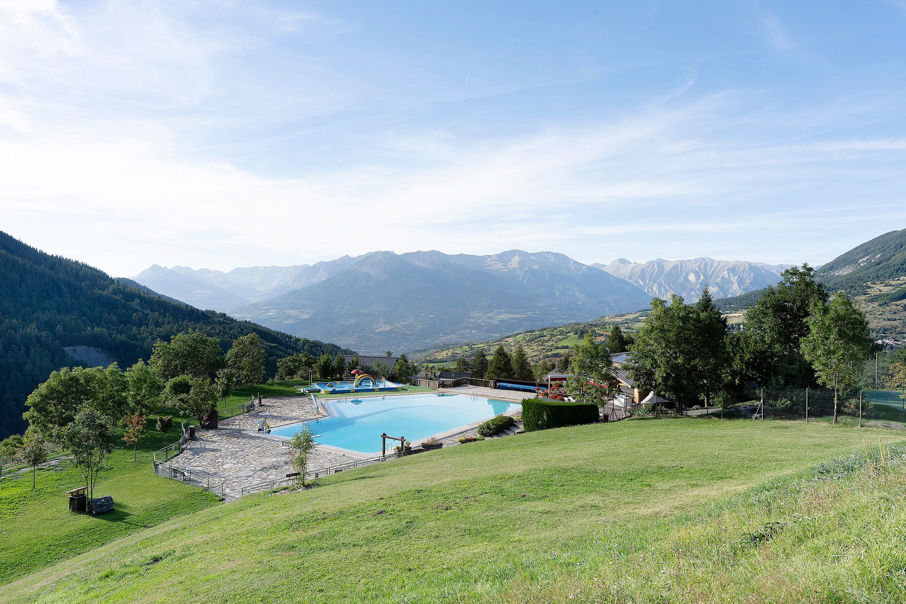 A pool surrounded by a stone deck, with mountains in the background.