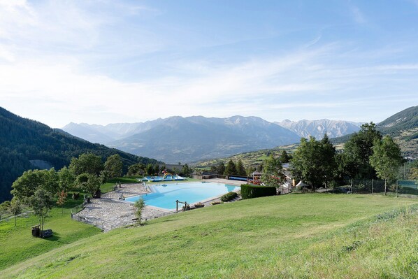 Ein Pool, umgeben von einer Steindeck, mit Bergen im Hintergrund.