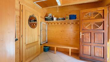 Een houten interieur met een bankje, een spiegel en een deur met ruit.