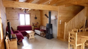 Ein Holzblockbau-Innenraum mit einer Couch, einem Tisch, einem Kamin und einer Treppe.