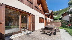 Un chalet en bois doté d’une terrasse, d’une table en bois et offrant une vue sur le paysage environnant.