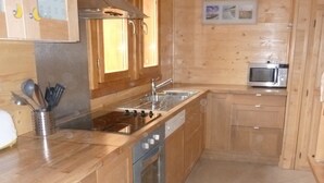 Eine Küche mit Holzschränken, einem Edelstahlherd, einer Mikrowelle und einem Spülbecken.