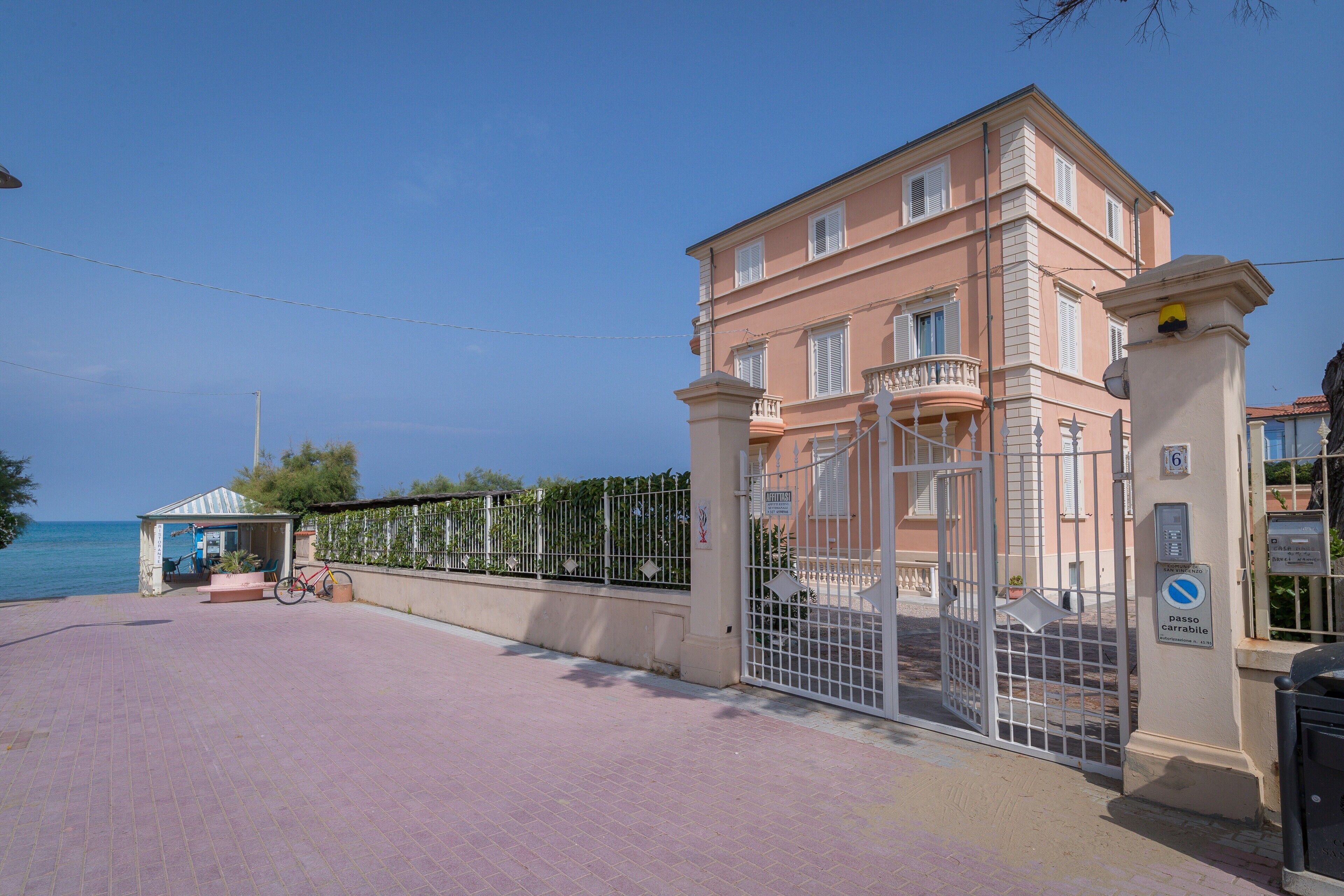 A coastal building with a gated entrance, a small kiosk, and a bicycle.
