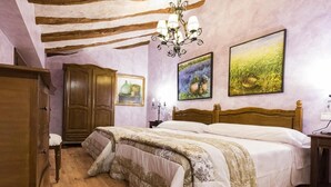 A bedroom with a wooden bed, a nightstand, a dresser, and a chandelier. - La Tahona: Sustainable Country House for Cyclists, Starlight-Certified in Lerín (Lerín)