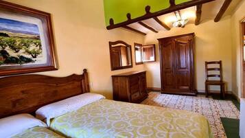 A bedroom with a bed, a wooden wardrobe, a chair, and a painting on the wall.