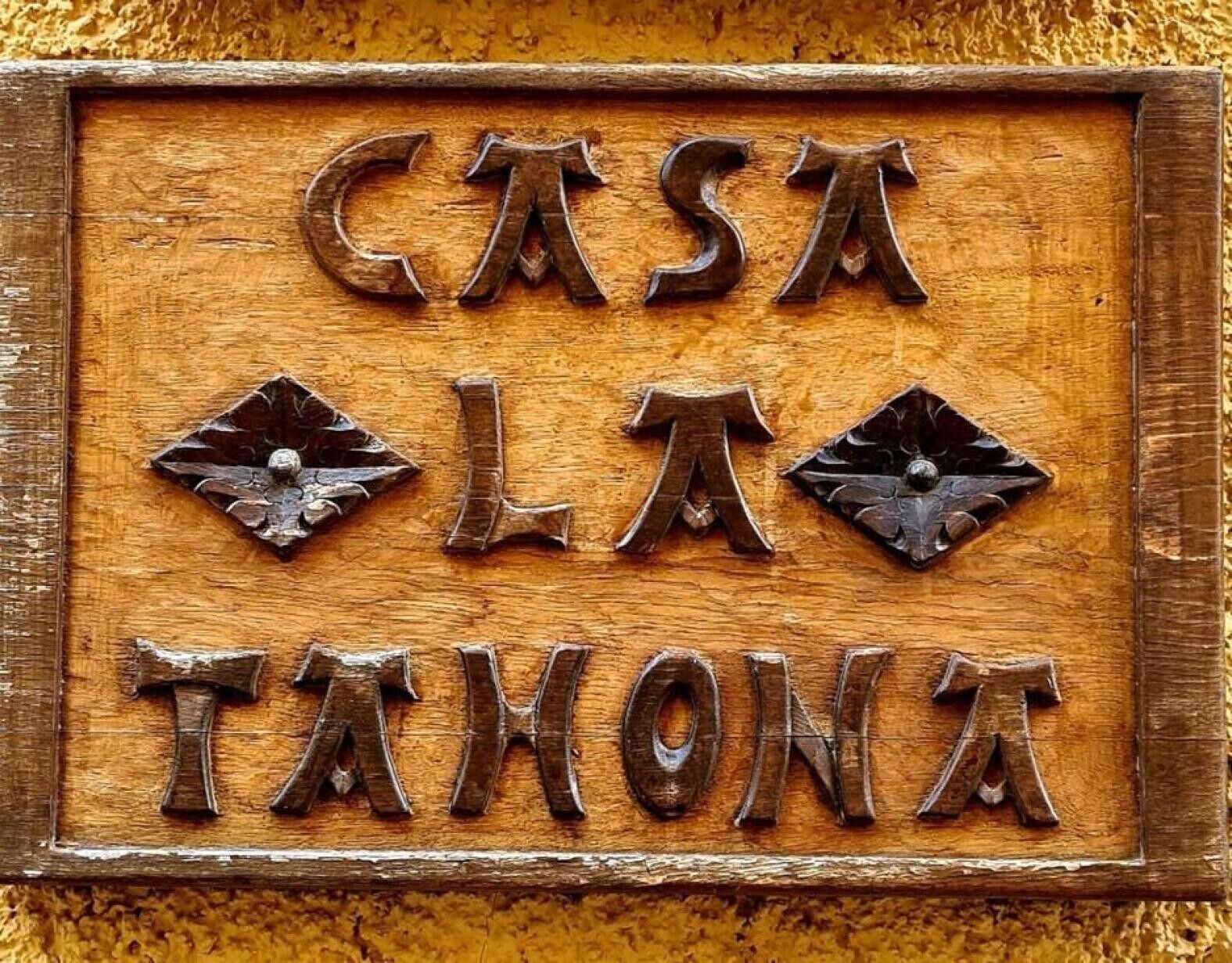Un letrero de madera con el texto 'CASA LA TANONA' en una fuente rústica.