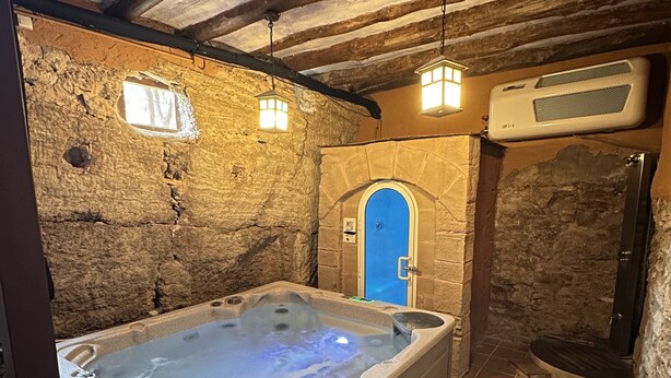 A stone-walled bathroom with a wooden bench, a bathtub, and a shower area. - La Tahona: Sustainable Country House for Cyclists, Starlight-Certified in Lerín (Lerín)