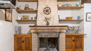 Een open haard met een stenen boogtrommel, houten kasten en planken met decoratieve objecten.