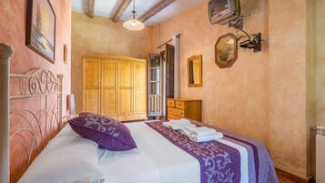 Un dormitorio con cama, armario de madera y televisión montada en la pared.