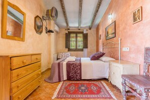 Un dormitorio con cama, cómoda de madera, mesita de noche y ventana con persianas.
