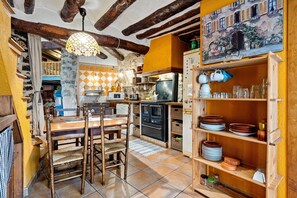 A rustic kitchen with exposed beams, a wooden dining table, and a tiled floor. - Country House 'Ca La Germandat Paüls' with Mountain View, Private Terrace and Wi-Fi (Pauls)