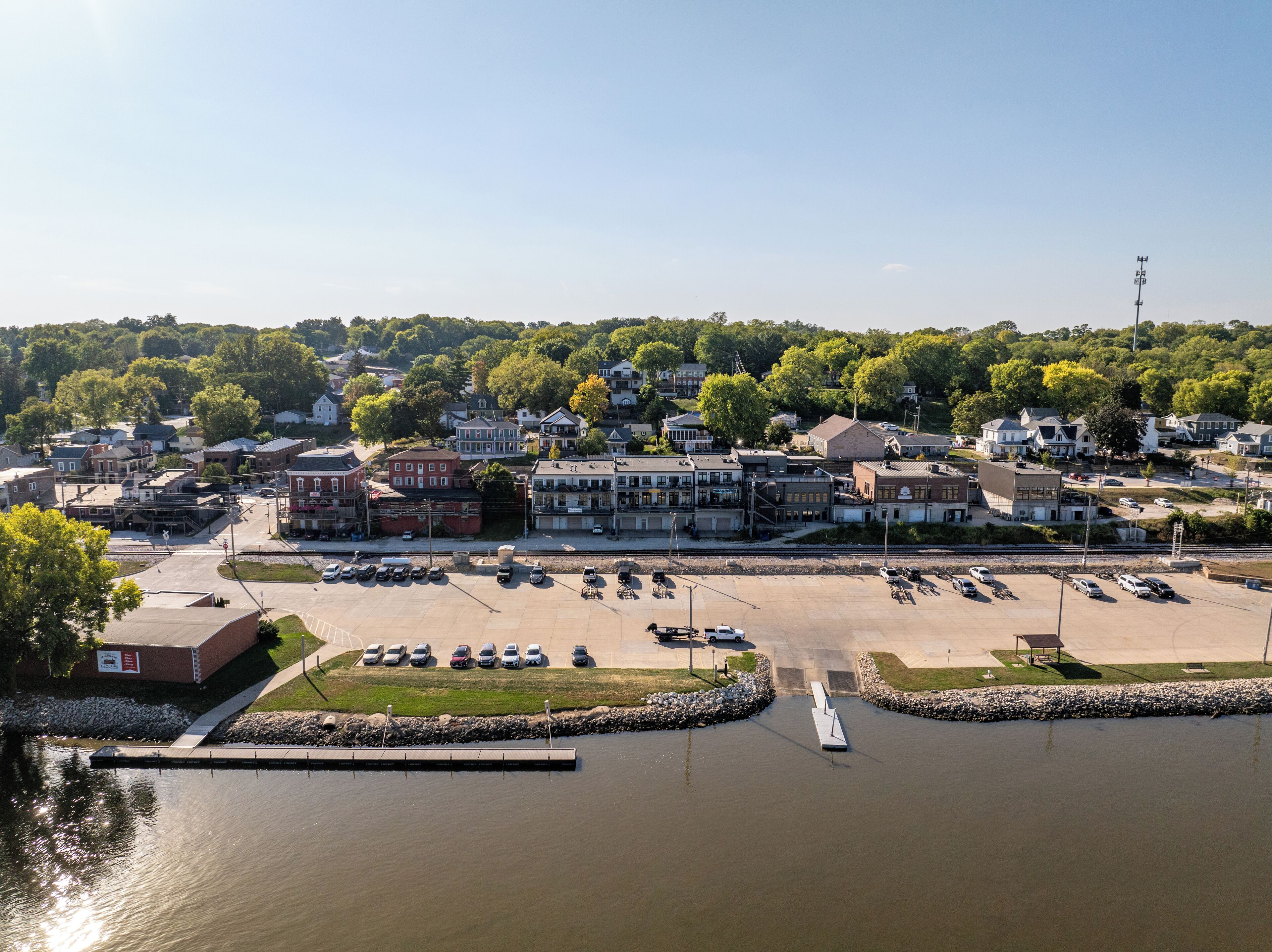 An aerial view of a town with a marina, parking areas, and buildings.