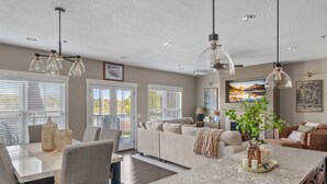 Eine moderne Küche mit Essbereich, ein Wohnzimmer mit Sofa und Couchtisch sowie eine große Kochinsel mit Pflanze.