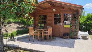 Una cabaña de madera con un patio, una mesa y sillas, y un radio.