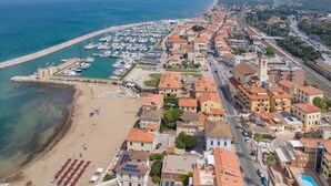 An aerial view of a coastal town with a marina, beach, and residential buildings. - Apartment 'Villa Corallo - Turchese' with Shared Garden, Wi-Fi and Air Conditioning (San Vincenzo)