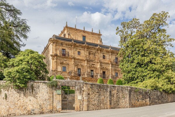 A historic building with a stone facade, multiple windows, and a gated entrance.