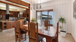 Una cocina moderna con armarios de madera, una mesa de comedor con sillas y una planta en maceta.