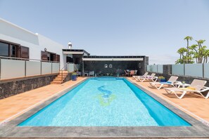 A swimming pool with lounge chairs, a stone wall, and a staircase leading to an upper level. - Vacation Villa 'Casa Los Llanos Teseguite Lanzarote' with Sea View, Private Pool and Wi-Fi (Teguise)