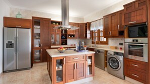 Una cocina con armarios de madera, un refrigerador de acero inoxidable, una lavadora y un horno empotrado.