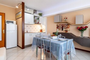 A dining area with a table set for four, a refrigerator, cabinets, and a kitchen counter. - Apartment 'Casa Vacanza Marina Di Pietrasanta' with Mountain View, Wi-Fi and Air Conditioning (Pietrasanta)