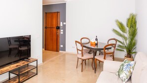 A living room with a TV, wooden chairs, a dining table, and a sofa. - 605A Residenza Gigli (Garda)