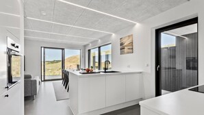 Una cocina moderna con una isla grande, puertas correderas que dan a un balcón y vistas al exterior.