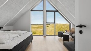 Un dormitorio moderno con un tragaluz grande, una cama, un escritorio y una silla.