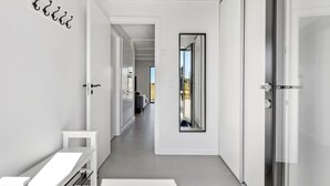 Un pasillo moderno con un banco, un espejo y una puerta que da a una habitación.