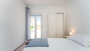 A bedroom with a bed, a nightstand with a lamp, a wardrobe, and a sliding glass door leading to an outdoor area. - Beautiful home in Sukosan (Sukosan)