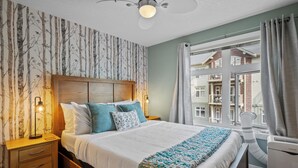 Ein Schlafzimmer mit einem großen Bett, einem Holzkopfteil und Blick auf Gebäude durch ein Fenster.