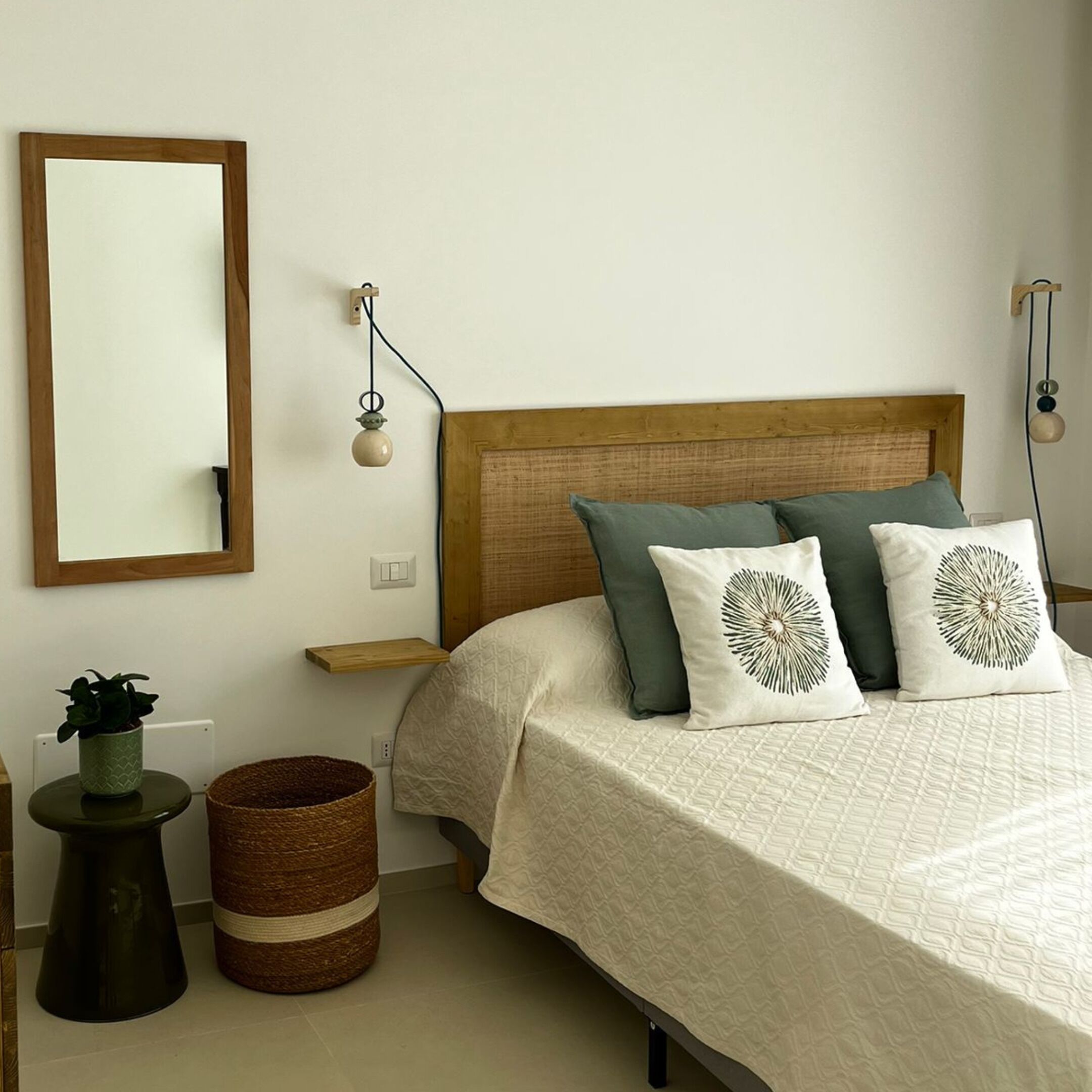 Un dormitorio con cabecera de madera, un espejo grande y dos mesitas de noche con lámparas de pared.