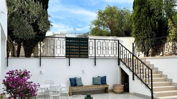 A patio with a white table and chairs, a bench with cushions, and a staircase. - Appartamento in villa, 2 camere da letto e cucina (Bari)