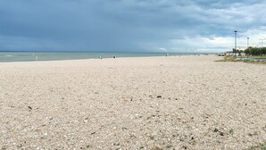 Een strand met kiezelstenen, een heldere lucht en een rustige zee.