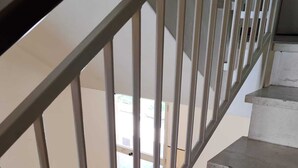 Een betonnen trap met metalen leuningen die leidt naar een open ruimte met een deur.