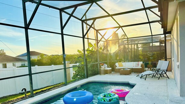A pool area with a glass enclosure, lounge chairs, and inflatable rings. - 15 Mint to Disney 2 mint to the Best golf courses. Family size villa.      (Davenport)