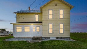A two-story house with a garage, a sloped roof, and a small front porch. - Country Charm on the Sandusky: Live Music Nearby (Fremont)