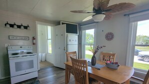 A kitchen with a white stove, wooden dining table, and chairs. There is a ceiling fan above the table. - Country Charm on the Sandusky: Live Music Nearby (Fremont)