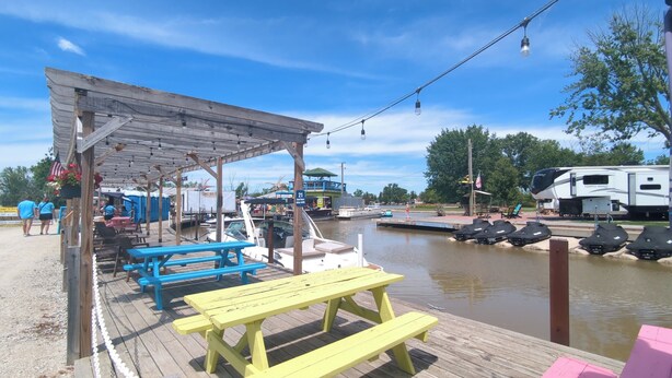 A dock with picnic tables, a covered seating area, and a boat docked nearby. - Country Charm on the Sandusky: Live Music Nearby (Fremont)