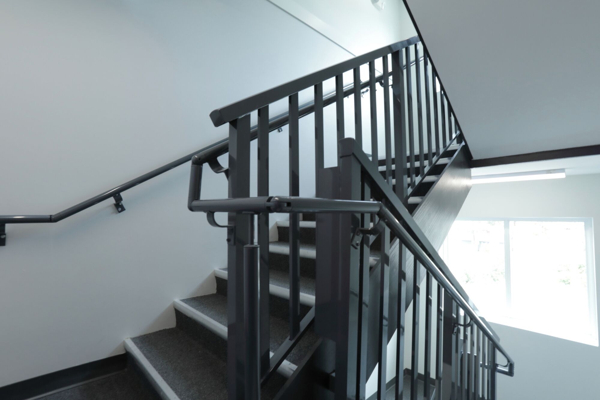 A staircase with a metal railing and carpeted steps.