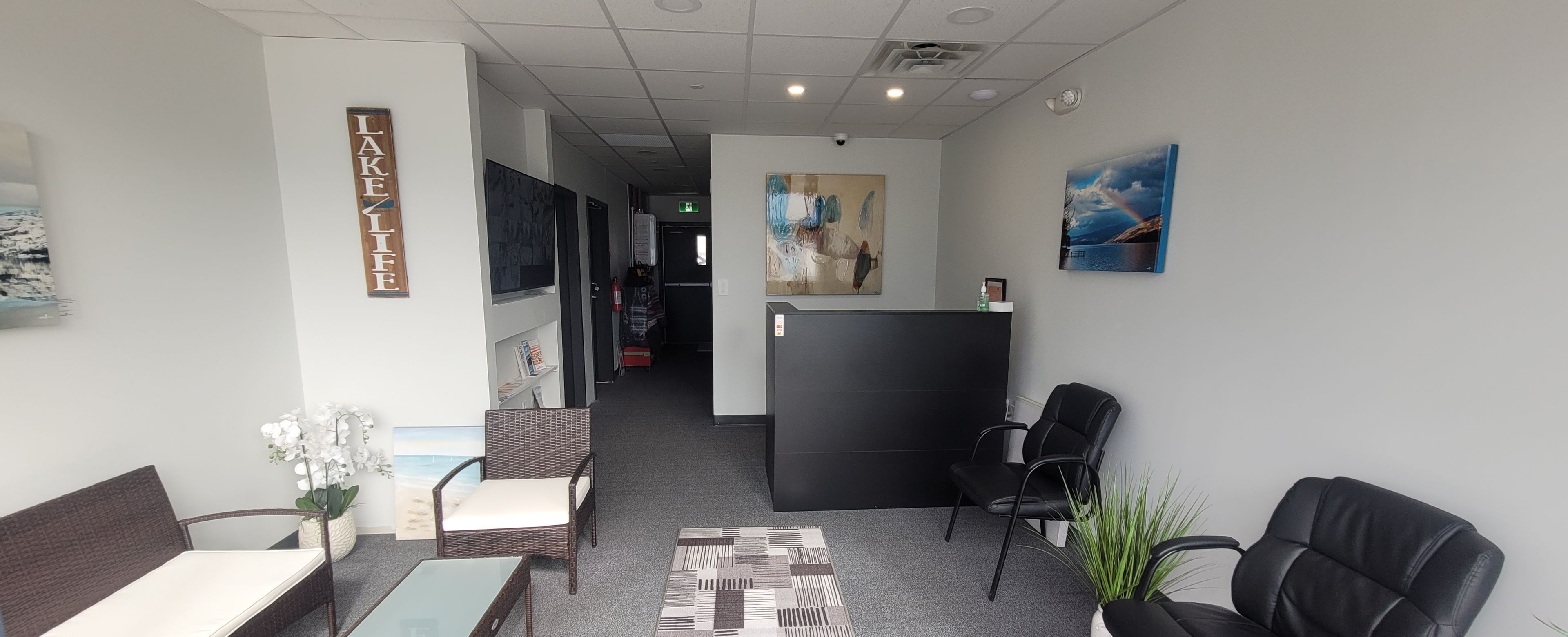 A hotel lobby with a reception desk, seating area, and artwork on the walls.